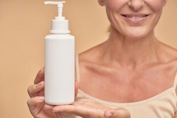 Happy lady showing off a moisturizing body cream in studio