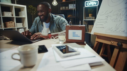 Fototapeta na wymiar Smiling african businessman finishing work in coworking. Happy afro guy relaxing