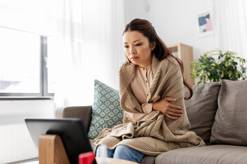 medicine, healthcare and technology concept - sick young asian woman having video call or online...
