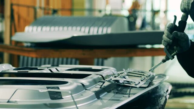 Car factory worker applying structural adhesive on a car part
