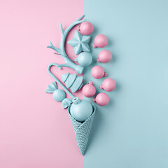 Creative Christmas layout made with ice cream cone and bauble ornaments on dual tone baby blue and pink pastel background. Minimal winter or New Year seasonal concept. Flat lay, top view.