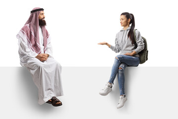 Saudi arab man in a thobe and a female student having a conversation and sitting on a blank panel