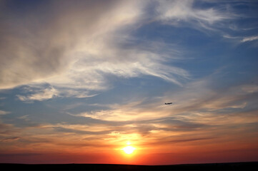 Beautiful sunset with clouds and a flying plane. Travel concept. Copy space for text.