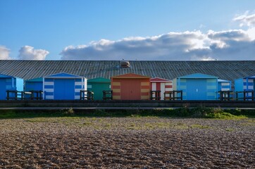 Colorful wooden beach huts at the coast of the seaside town Whitstable in Kent, England, blue sky...
