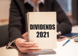 Business woman holds a notebook with the text - dividends 2021.