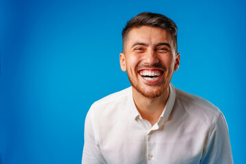 Young positive european man standing in blank white shirt laughing