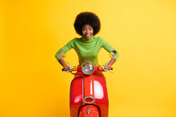 Photo portrait of excited woman driving bike forward isolated on vivid yellow colored background