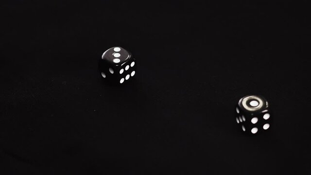 Gamer hand throwing black double dice on dark background. Rolling dice in night casino. Close up dice gambling on dark casino table