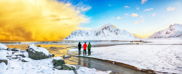 Group of tourist looking fabulous winter scenery on Skagsanden beach with illuminated clouds during...