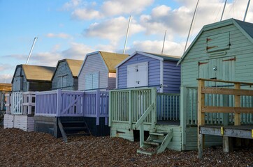 Colorful wooden beach huts at the coast of the seaside town Whitstable in Kent, England, blue sky...