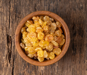 Raisins in wooden bowl on a wooden background