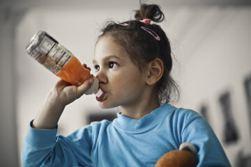 
little girl drinks from a bottle juice