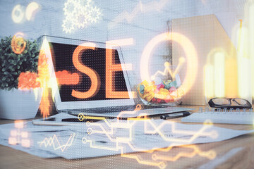 Double exposure of table with computer and seo drawing hologram. Search optimization concept.