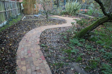  Landscape garden path way winding two fork lanes antique recycled reclaimed house bricks, cut in grass with family detached 1930s house in background with patio trees plants bush