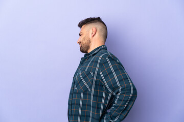 Caucasian man isolated on purple background suffering from backache for having made an effort