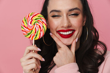Joyful beautiful brunette girl smiling and holding lollipop