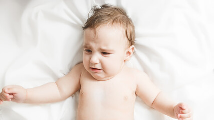 Childish sadness. crying baby, cute cute little girl crying lying on the bed at home. Childhood concept.