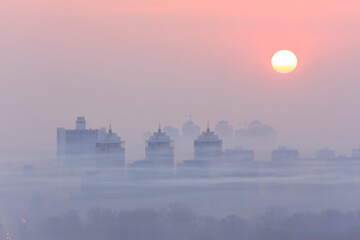 Blurred outlines of the city at dawn in smog
