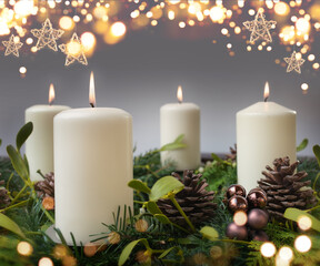 Four burning candle in a advent wreath of fir branches with christmas ornament and golden bokeh....