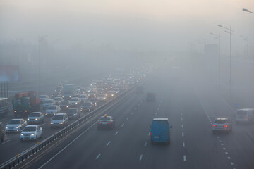 cars driving in the city in the morning mist