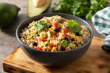 Mexican salad with quinoa in bowl on wooden table
