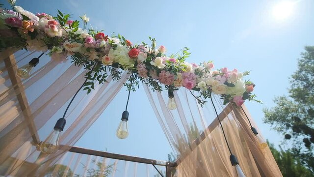 Wedding decor. Beautiful wedding arch with fresh flowers in the garden on a summer sunny beautiful wedding day