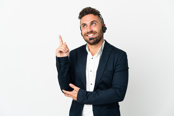Telemarketer man working with a headset isolated on white background pointing up a great idea