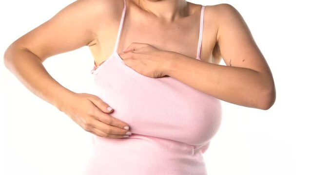 big breasted woman adjusting her breasts under the shirt on white background