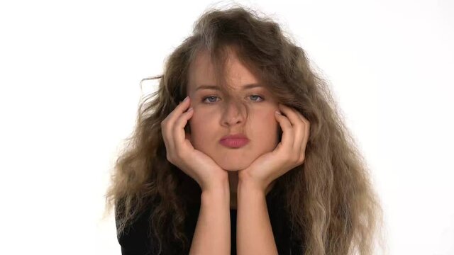 a funny young bored woman blowing her hair on a white background