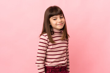 Fototapeta premium Little girl isolated on pink background having doubts while looking side