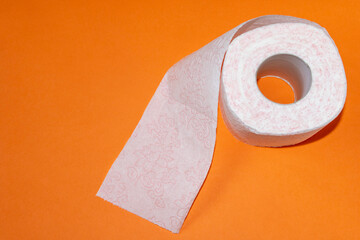 A roll of toilet paper on orange background. Close up.