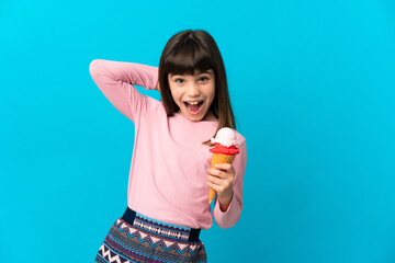 Little girl with a cornet ice cream isolated on blue background laughing