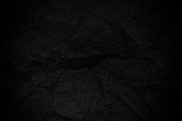 Black crumpled sheet of paper background.