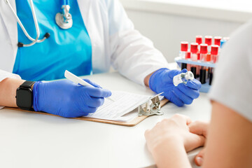 Hands of a doctor holding blood sample and making notes