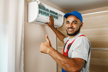 Professional repairman installing air conditioner in a room - obrazy, fototapety, plakaty