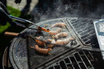 A professional cook prepares shrimps on the grill outdoor, food or catering concept
