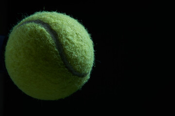 Green tennis ball on black background