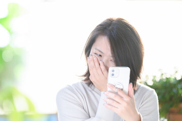 スマホの連絡に衝撃を受ける30代～40代の日本人の主婦(女性)コピースペースあり