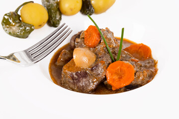 a delicious looking beef stew with a fork and out of focus vegetables. homemade food concept.