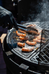 A professional cook prepares shrimps on the grill outdoor, food or catering concept