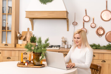 Happy woman looking in laptop in front of Christmas interior
