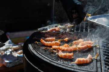 A professional cook prepares shrimps on the grill outdoor, food or catering concept