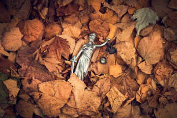 Lady Justice statue in pile of dry autumn leaves