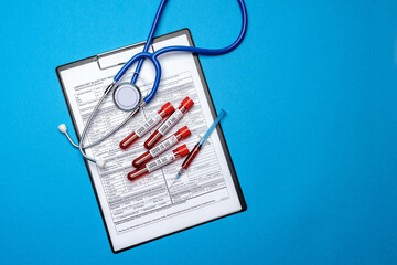 Clipboard with paper blank form with medical tools on blue background with cope space