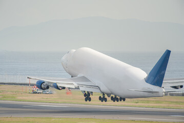 an cargo airplane getting to take off from airport with sea background and bright light tone