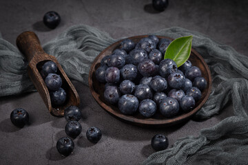 Dish with a bunch of blueberries on  dark background.
