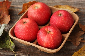Juicy red apples and autumn leaves on the table