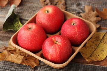 Juicy red apples and autumn leaves on the table