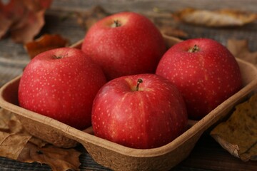 Juicy red apples and autumn leaves on the table