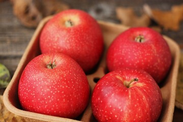 Juicy red apples and autumn leaves on the table